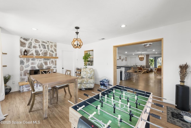 game room featuring a fireplace, hardwood / wood-style floors, and a notable chandelier