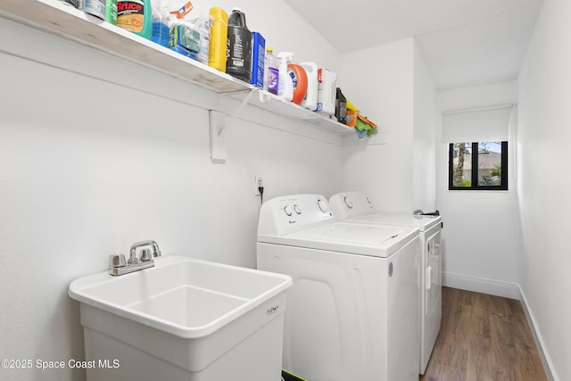 clothes washing area with wood-type flooring, separate washer and dryer, and sink