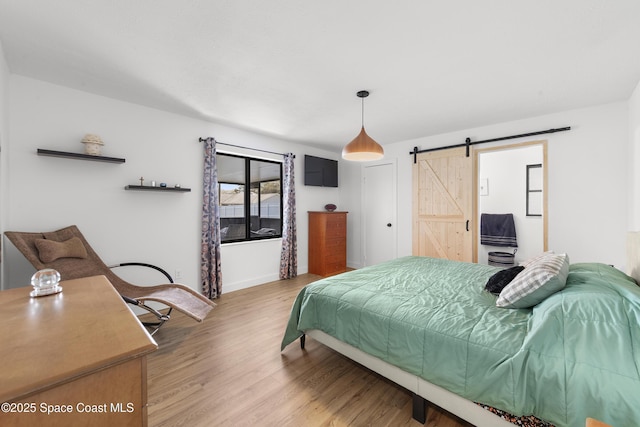 bedroom with hardwood / wood-style flooring and a barn door