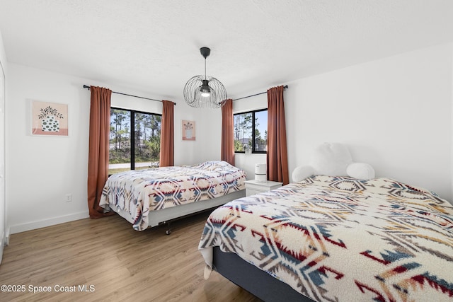 bedroom with access to exterior, a textured ceiling, multiple windows, and light hardwood / wood-style flooring