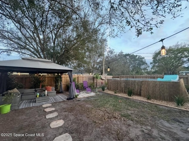 view of yard featuring a gazebo, a fenced backyard, an outdoor living space, and a patio area