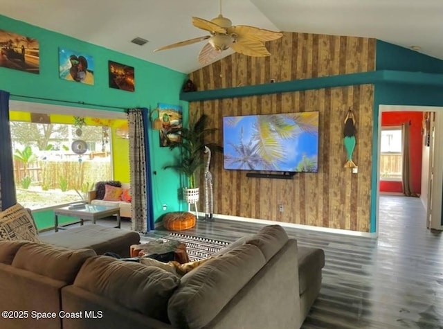 living room with hardwood / wood-style flooring, ceiling fan, lofted ceiling, and wooden walls