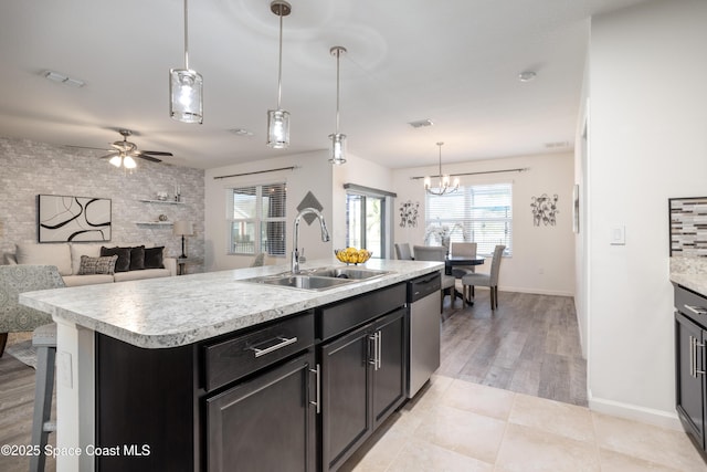 kitchen featuring dishwasher, pendant lighting, sink, and a center island with sink