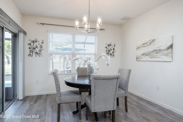 dining area featuring wood-type flooring and an inviting chandelier