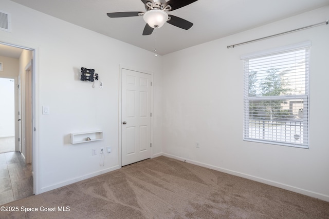 carpeted spare room featuring ceiling fan