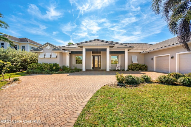 mediterranean / spanish-style home featuring a garage and a front lawn