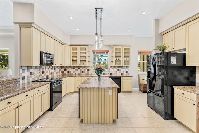 kitchen featuring hanging light fixtures, a center island, light stone counters, tasteful backsplash, and black appliances