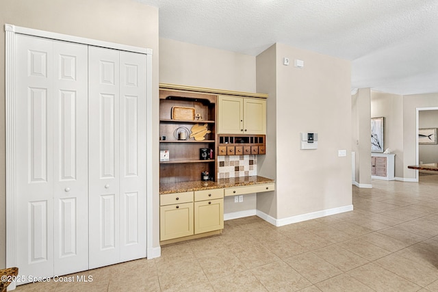 kitchen featuring cream cabinets, built in desk, and a textured ceiling