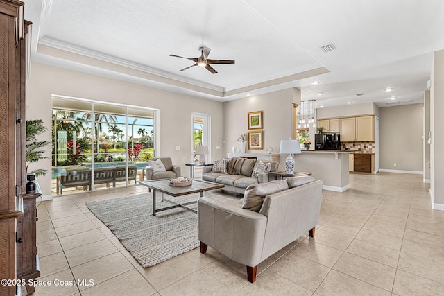 living room featuring a raised ceiling, crown molding, and light tile patterned floors