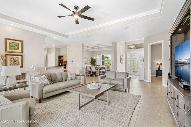 living room with light tile patterned flooring, ornamental molding, and a tray ceiling