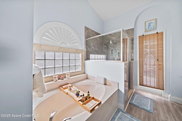 bathroom with lofted ceiling, shower with separate bathtub, and wood-type flooring