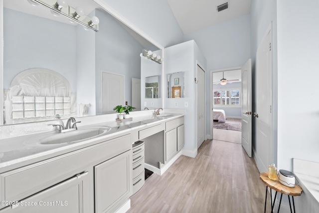 bathroom featuring a high ceiling, vanity, wood-type flooring, and ceiling fan