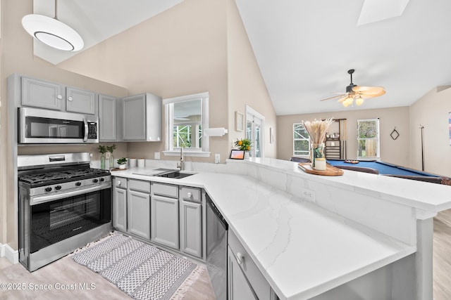 kitchen with appliances with stainless steel finishes, sink, gray cabinetry, and kitchen peninsula