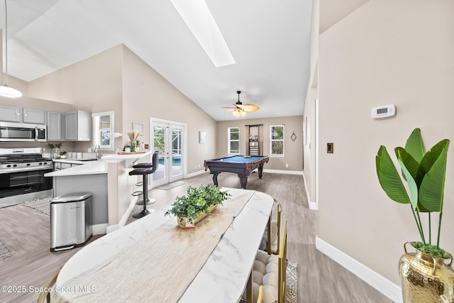 dining space featuring sink, billiards, a skylight, light hardwood / wood-style floors, and french doors