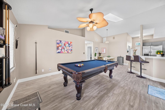 game room with billiards, vaulted ceiling with skylight, ceiling fan, and light hardwood / wood-style flooring