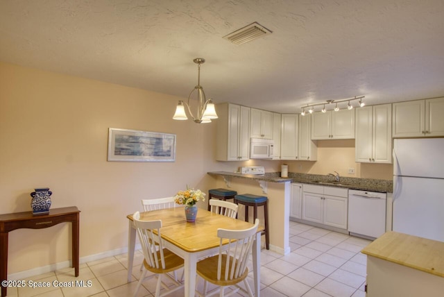 kitchen with light tile patterned flooring, white cabinetry, sink, kitchen peninsula, and white appliances