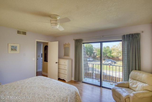 bedroom featuring hardwood / wood-style flooring, ceiling fan, access to exterior, and a textured ceiling