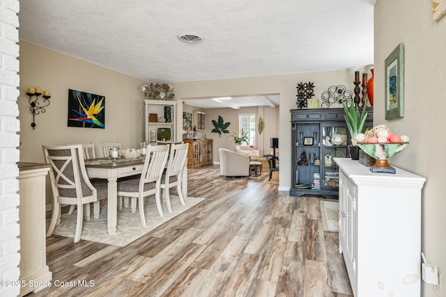 dining space featuring hardwood / wood-style floors and a textured ceiling