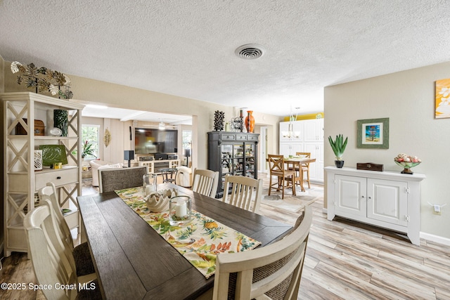 dining space with light hardwood / wood-style floors and a textured ceiling