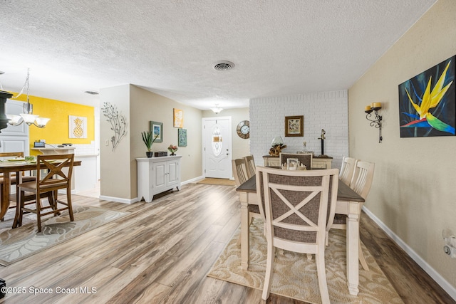 dining space featuring a notable chandelier, hardwood / wood-style flooring, and a textured ceiling