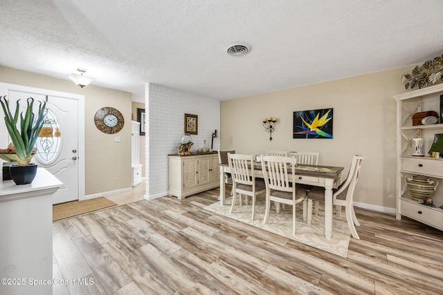 dining space with light hardwood / wood-style floors and a textured ceiling