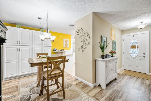 interior space featuring a textured ceiling, a chandelier, and light hardwood / wood-style flooring