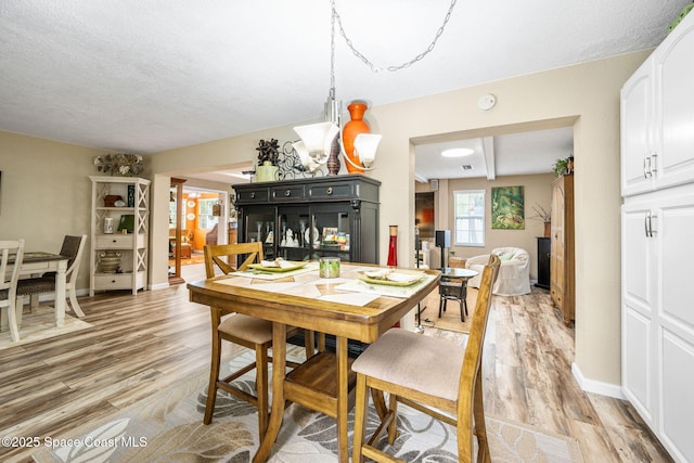 dining area featuring a multi sided fireplace, a textured ceiling, and light wood-type flooring