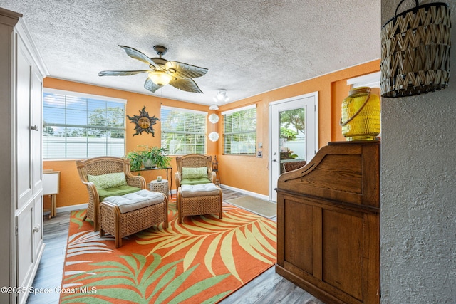 living area with a textured ceiling, ceiling fan, and light hardwood / wood-style flooring