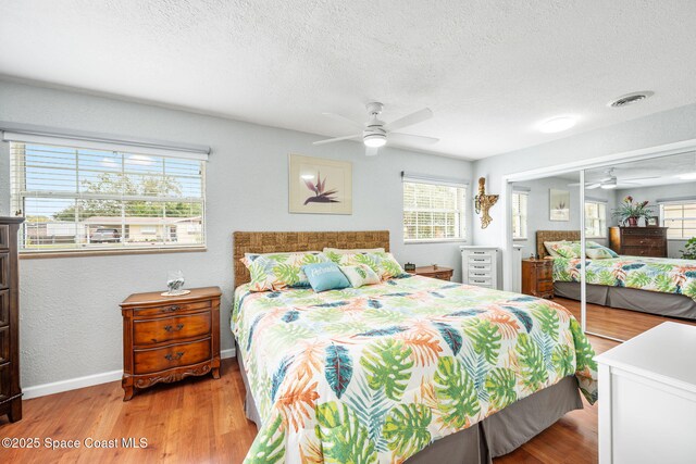 bedroom with ceiling fan, light hardwood / wood-style flooring, a closet, and a textured ceiling