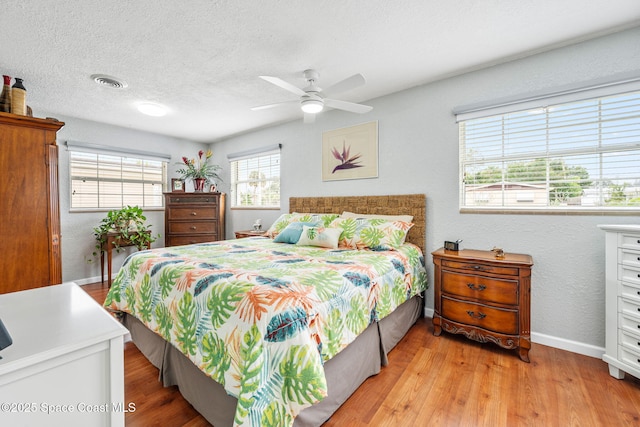 bedroom featuring ceiling fan, a textured ceiling, and light hardwood / wood-style floors