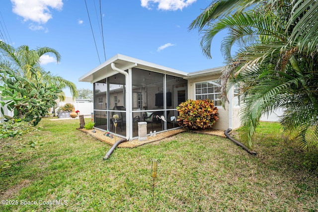 back of house featuring a yard and a sunroom