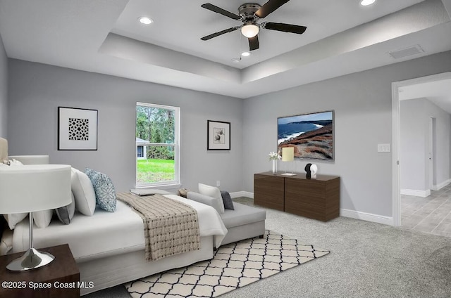 bedroom featuring light carpet, a tray ceiling, and ceiling fan