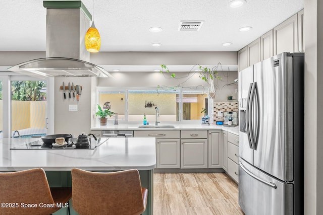 kitchen featuring visible vents, a sink, stainless steel appliances, light wood-type flooring, and island range hood