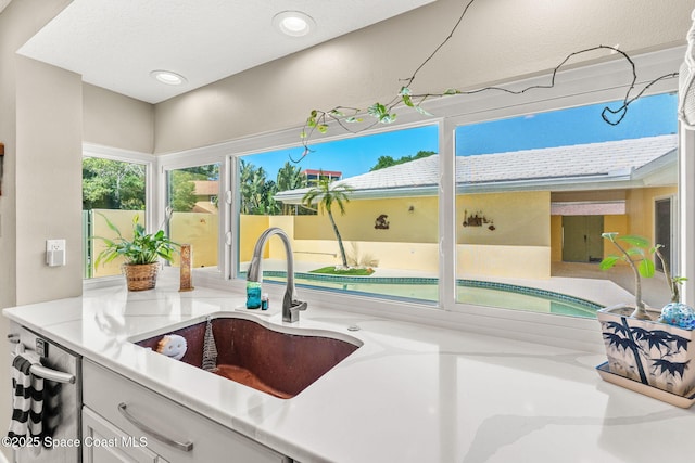 kitchen with recessed lighting, dishwasher, light countertops, and a sink