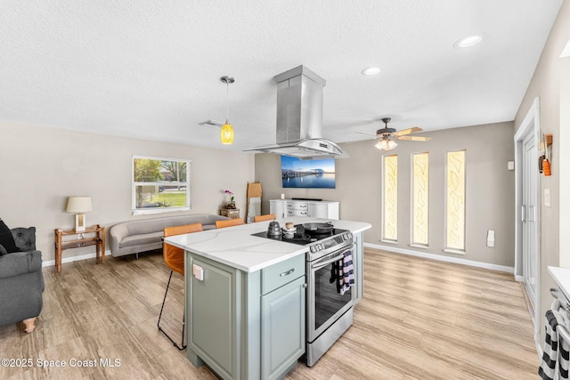 kitchen featuring open floor plan, light wood-style floors, stainless steel electric range, a breakfast bar area, and island range hood