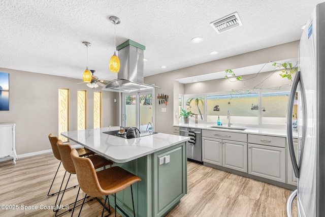 kitchen featuring visible vents, a center island, island exhaust hood, stainless steel appliances, and a sink