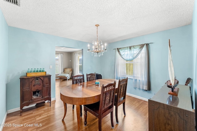 dining room featuring baseboards, visible vents, and light wood finished floors