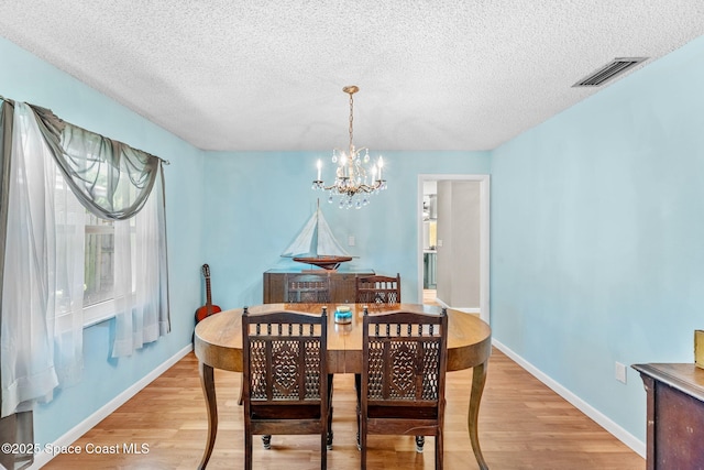 dining room with an inviting chandelier, light wood-style flooring, baseboards, and visible vents