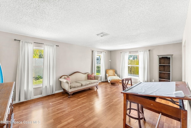 living area featuring visible vents, a textured ceiling, and light wood-style floors