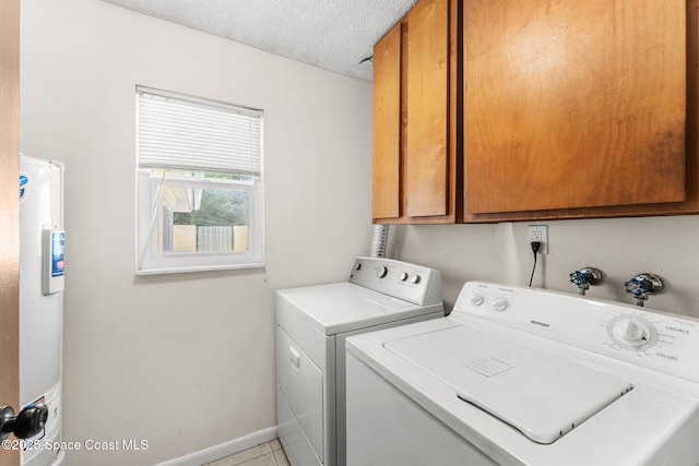 washroom featuring independent washer and dryer, electric water heater, a textured ceiling, cabinet space, and baseboards