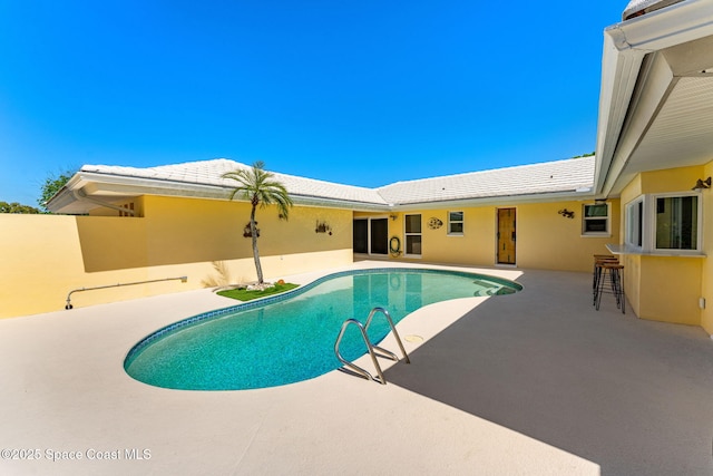 outdoor pool with outdoor dry bar and a patio area