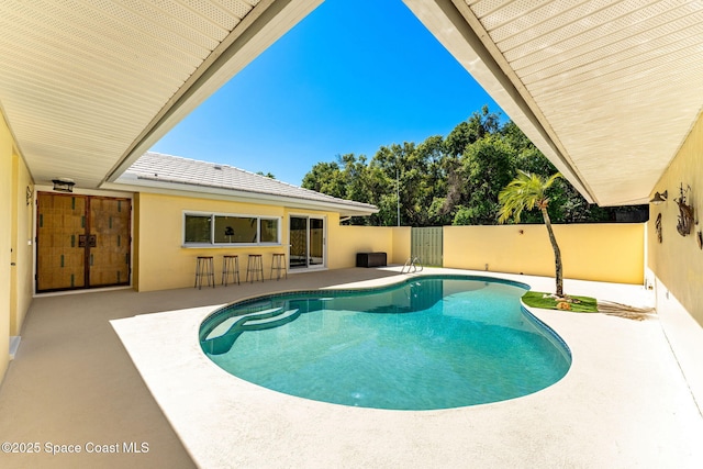 view of pool with a patio area, a fenced in pool, outdoor dry bar, and fence