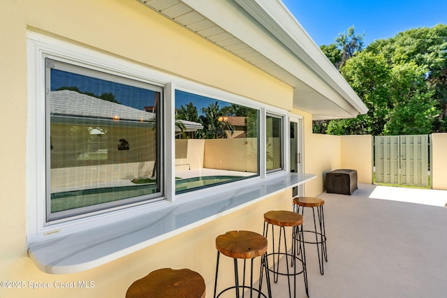 view of patio with outdoor dry bar and fence