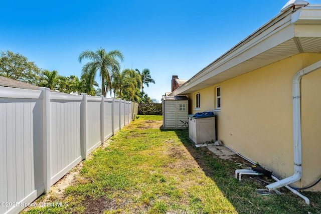 view of yard featuring an outbuilding, a storage shed, and fence