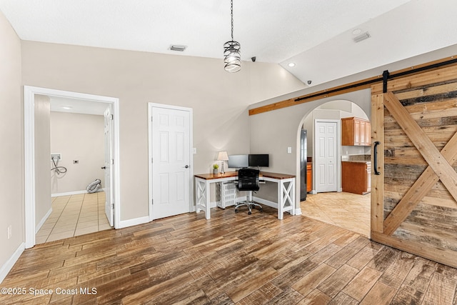 office with vaulted ceiling, a barn door, and wood-type flooring