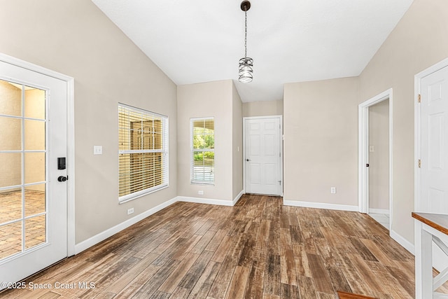 unfurnished dining area with vaulted ceiling and dark wood-type flooring