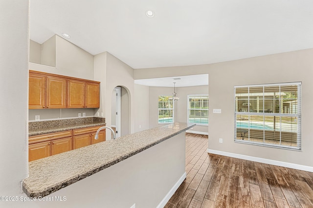 kitchen with hanging light fixtures, dark wood-type flooring, sink, and a center island