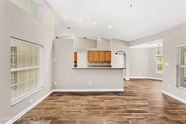 unfurnished living room with dark hardwood / wood-style floors, a chandelier, and high vaulted ceiling