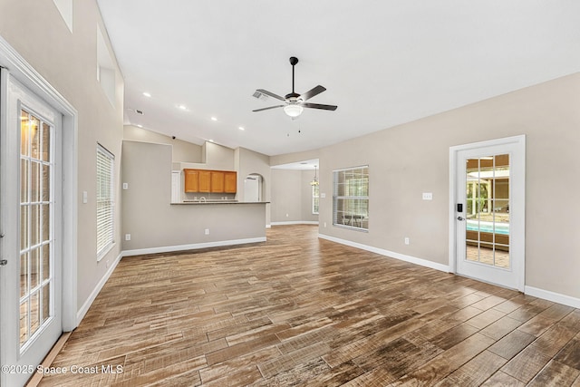 unfurnished living room with lofted ceiling, hardwood / wood-style floors, and ceiling fan