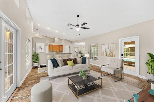 living room featuring ceiling fan, vaulted ceiling, and light wood-type flooring